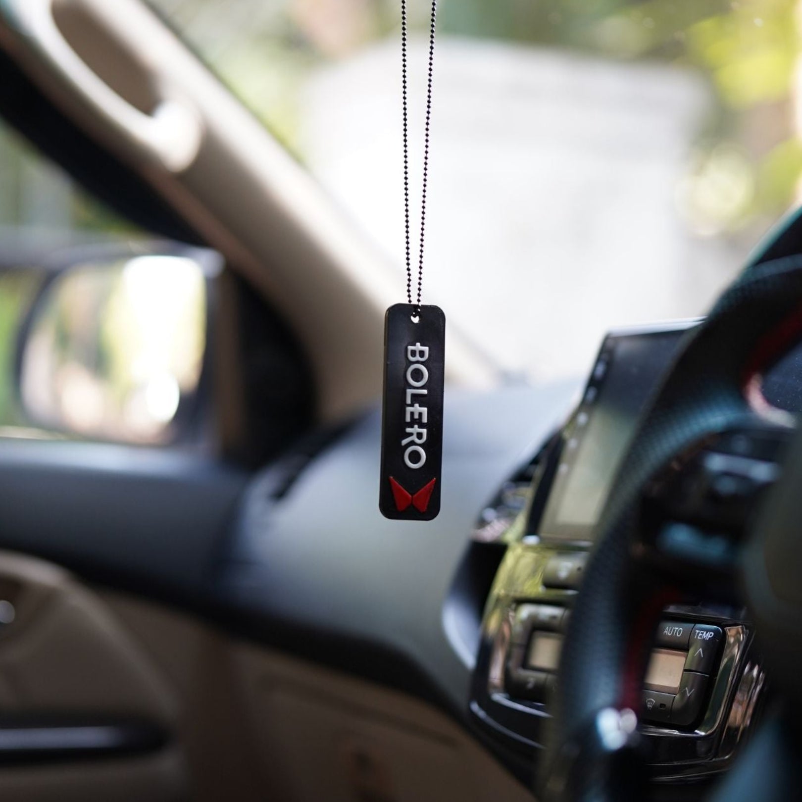 Car air freshener hanging from a car's rearview mirror with 'BOLERO' branding.