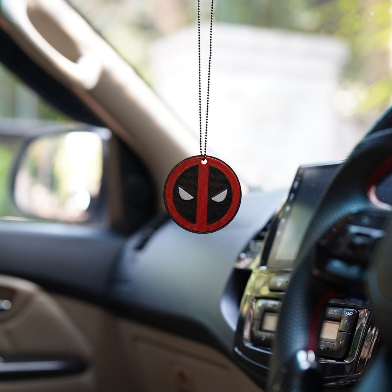 Deadpool logo air freshener hanging in a car interior