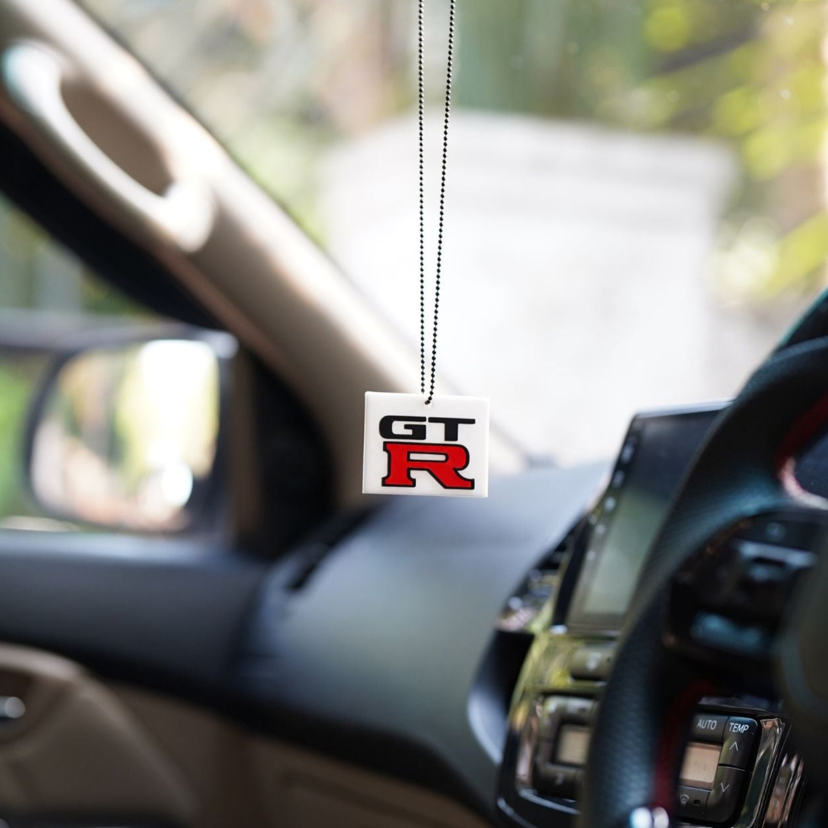 Car interior with a GT-R branded car air freshener hanging from the rearview mirror.