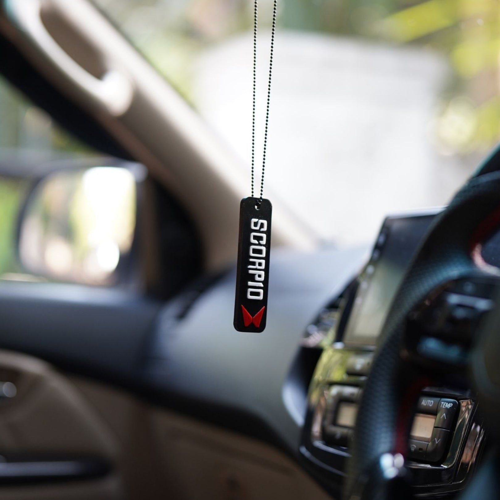 Car interior with a Scorpio air freshener hanging from the rearview mirror.