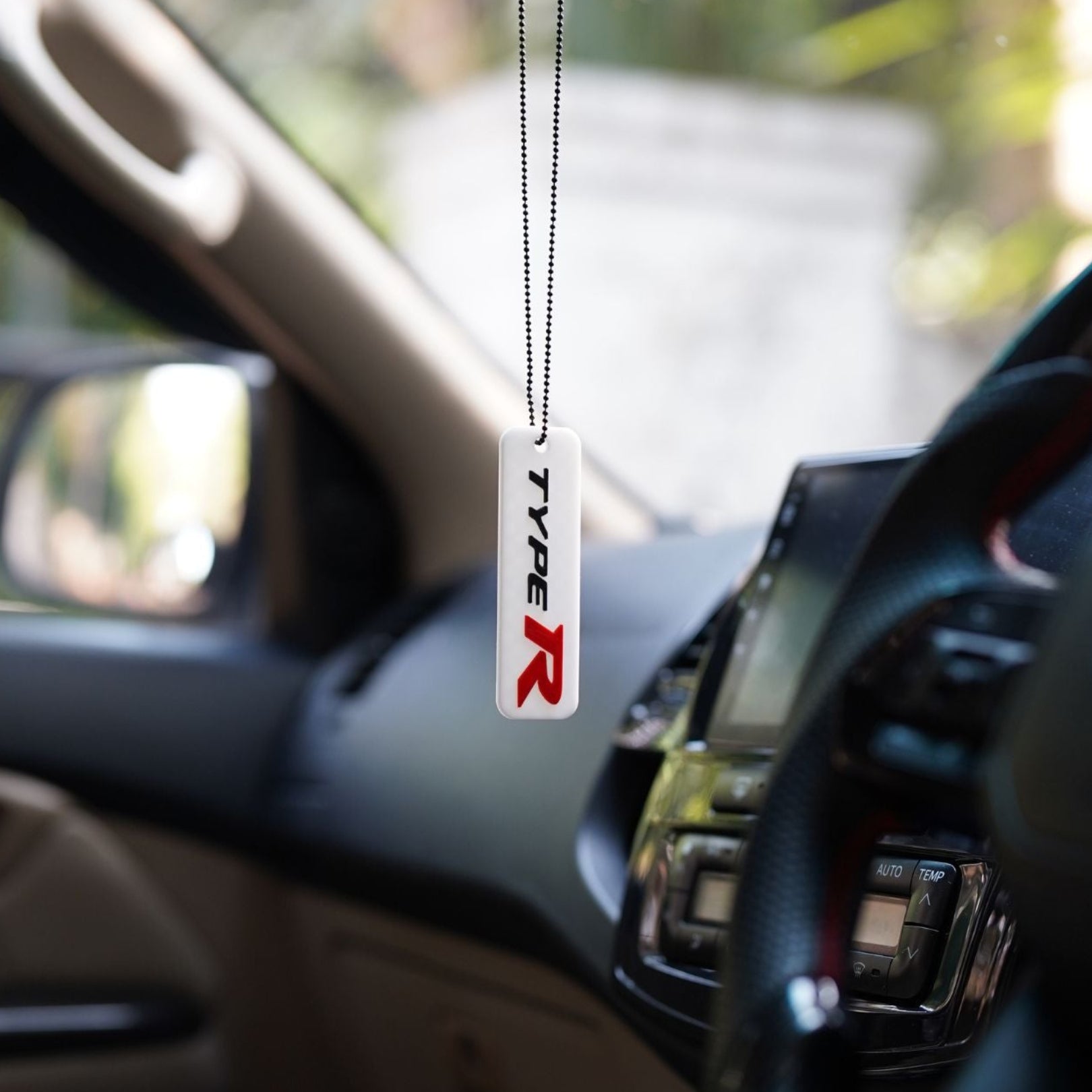 Car air freshener with 'TYPE R' logo hanging from a car's rearview mirror.